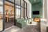 Modern apartment lounge featuring a stylish green sofa, inviting bean bag chair, and a sleek wall-mounted TV. A cozy workspace with natural light flows seamlessly in the background.