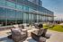 Luxurious rooftop terrace with modern seating, green artificial turf, and expansive glass windows offering stunning skyline views.