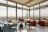 Luxurious high-rise living room with panoramic floor-to-ceiling windows and elegant modern furnishings, overlooking a vibrant urban landscape.