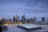 Modern rooftop patio with a luxurious pool offering stunning city skyline views at dusk.