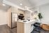 Modern kitchen with sleek stainless steel appliances, cozy bar seating, elegant pendant lighting, and stylish natural wood cabinetry.