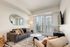 Modern chic living room with stylish decor, featuring a cozy gray sofa, geometric-patterned rug, and expansive city view through large windows.