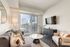 Modern living room with a cozy sofa, stylish armchair, and elegant decor, featuring a large window with a city view.