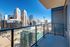 Luxurious apartment balcony with stunning city skyline views, featuring modern glass railings and vibrant urban landscape.
