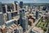 Stunning aerial view of a vibrant cityscape with towering modern skyscrapers, lush green parks, and bustling streets.