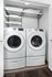 Modern laundry closet with sleek white washer and dryer, equipped with functional shelving for storage.