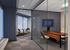 Modern office space featuring a glass partition with a sleek desk and comfortable seating, complemented by a cozy meeting nook with a round table and chairs.