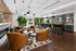 Luxurious modern lounge with stylish leather armchairs, a chic bar area, and vibrant greenery creating an inviting atmosphere.