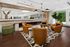 Modern lounge with elegant leather chairs, stylish geometric rug, and vibrant greenery, offering a cozy and inviting atmosphere.