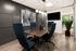 Modern conference room with sleek dark wood table, blue high-back chairs, contemporary pendant lighting, and vibrant abstract artwork.