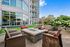 Modern apartment courtyard with cozy seating around a stylish stone firepit and lush greenery, perfect for relaxing outdoors.