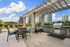 Chic rooftop patio with pergola, modern grill, and city skyline views, perfect for entertaining.