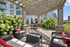 Charming outdoor patio with wicker furniture, lush greenery, and a wooden pergola adorned with string lights, perfect for relaxation and gatherings.