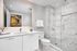 Elegant bathroom with luxurious marble shower, modern vanity, and ample mirror reflecting stylish artwork.