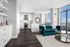 Sophisticated open-concept living space with elegant kitchen, plush teal sofa, and panoramic city views from large windows.
