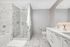 Luxurious modern bathroom with elegant marble tiles, spacious glass shower, and sleek vanity with under cabinet lighting.