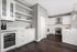 Elegant and modern kitchen featuring sleek white cabinets, polished marble countertops, and state-of-the-art appliances, enhanced by a warm wood floor.