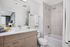 Modern bathroom with sleek wood vanity, polished fixtures, and bright, airy design.