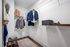 Spacious walk-in closet with elegant suits, organized shelving, and a cozy stool, perfect for a luxurious lifestyle.