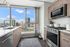 Modern kitchen with sleek appliances and floor-to-ceiling windows offering stunning city views.