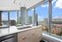 Modern kitchen with sleek countertops and panoramic city views, featuring elegant lighting and a stylish interior.