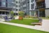 Vibrant courtyard space featuring lush green lawn, outdoor seating, grill area, and fun games like giant Connect Four and cornhole.