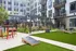 Modern apartment courtyard featuring lush green lawn, stylish seating with benches, and vibrant outdoor games area, perfect for relaxation and entertainment.