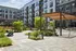 Modern apartment complex featuring a lush outdoor courtyard with seating areas, vibrant greenery, and stylish architecture.
