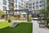 Modern apartment courtyard with lush green lawn, stylish seating, and elegant landscaping, perfect for relaxation and leisure.