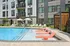 Luxurious apartment complex with inviting poolside loungers, stylish cabana, and relaxing lounge chairs under umbrellas, perfect for sunny days.