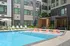 Luxurious apartment complex featuring a pristine swimming pool with chic lounge chairs and cozy shaded cabanas in a modern courtyard setting.