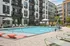 Modern apartment complex featuring a luxurious outdoor pool area with stylish lounge chairs and umbrellas, perfect for relaxation and leisure.