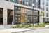 Modern apartment building exterior with sleek glass entrance, stylish brickwork, and lush landscaping.