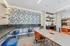 Vibrant and modern kitchen area featuring bold floral wallpaper, sleek countertops, and stylish seating with a pop of color.