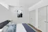 Elegant bedroom with crisp white walls, plush blue bedding, modern art, and double closets, creating a serene and stylish retreat.