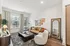 Chic and cozy living room featuring a plush brown leather sofa, elegant accent chairs, and modern decor. Large windows invite natural light, illuminating the stylish art pieces and contemporary floor lamp on a rich wooden floor.