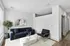 Modern living room with a navy blue sofa, stylish armchair, and elegant decor accentuated by natural light and chic artwork.