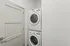 Sleek and modern laundry room featuring a compact stackable washer and dryer set against a pristine white backdrop.