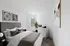Elegant bedroom with modern decor, featuring a plush bed, abstract wall art, and abundant natural light from a large window.