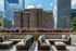 Chic urban patio with modern wicker seating and vibrant flower display, framed by a backdrop of stunning city skyscrapers.