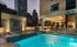 Luxurious urban rooftop pool with stunning city skyline view, surrounded by elegant lounge chairs and modern architecture.