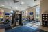 Bright, modern fitness center with state-of-the-art equipment, flat-screen TVs, and ample natural light from floor-to-ceiling windows.