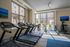 Modern gym facility with large windows, equipped with treadmills, exercise bikes, and inviting urban views.