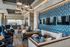 Luxurious modern lounge area with elegant seating, stylish lighting, and a feature wall of artistic tiles and multiple flat-screen TVs.