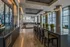 Elegant modern interior with a sleek design, featuring a long dining table, artistic wall decor, and large windows providing ample natural light.