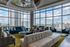 Luxurious high-rise apartment lounge with plush seating and panoramic city views through floor-to-ceiling windows.