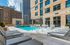 Luxurious rooftop swimming pool area with modern lounge chairs, surrounded by cityscape views and vibrant greenery.