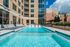 Luxurious apartment pool area with sun loungers, modern glass facade, and relaxing urban vibes.
