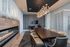 Elegant dining area with a sleek wooden table, surrounded by modern chairs and a chic linear fireplace, under a stylish chandelier.