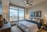 Luxurious bedroom with a king-sized bed, stylish decor, and a breathtaking city view through large windows, perfect for peaceful relaxation.